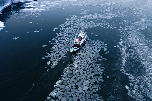Tug boat pushing through the ice on a sea in winter