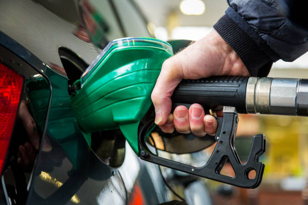 Refueling the car at the gas station Close up color image depicting a man's hand holding the hose and filling up his car with gas at the petrol station. Room for copy space. fuel pump photos stock pictures, royalty-free photos & images
