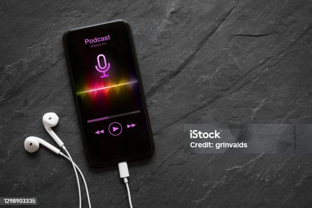 Earphones And Mobile Phone With Podcast App On Screen Stock Photo - Download Image Now