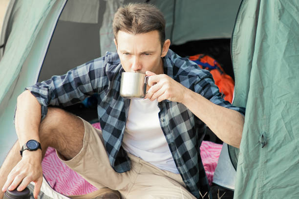 istock Pensive man drinking tea, sitting in tent and looking away 1298903343