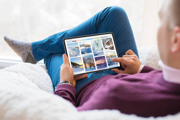 istock Man browsing beautiful winter photos on tablet at home 1298903390