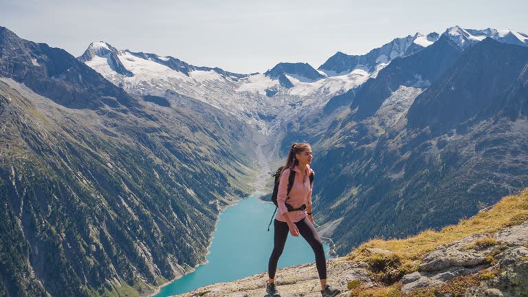 Fit athlete maintaining a healthy lifestyle, taking a walk uphill in mountain terrain over rocky trails surrounded with amazing scenery