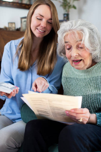 mujer más joven ayudando a vecino mayor con facturas y papeleo - care community 80 plus years cheerful fotografías e imágenes de stock