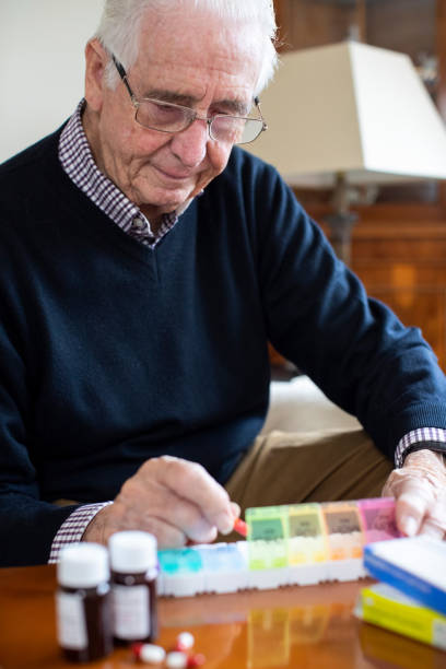 istock Senior Man At Home Organizing Medication Into Pill Dispenser 1298906579