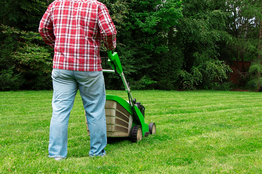 A man mowing the lawn. Cutting grass. Man working on a backyard. Man cutting grass in the garden with lawn mower.