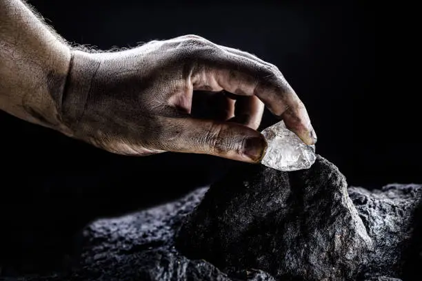 Photo of hand removing rare stone from a mine, chinese diamond digging