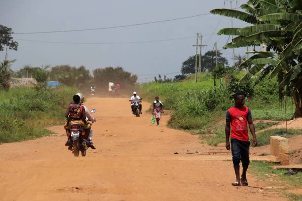 Motorbike taxis and pedestrian on the raod near Okpahoué in Togo, West Africa. Okpahoué, Togo - June 29, 2019: Motorbike taxis and pedestrian on the raod near Okpahoué in Togo, West Africa. togo stock pictures, royalty-free photos & images
