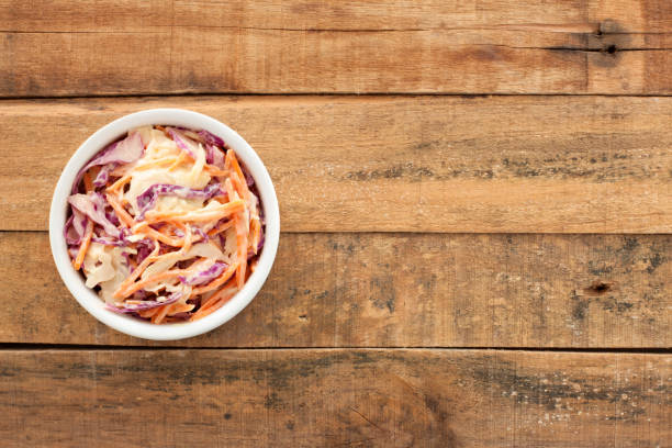 Coleslaw salad Top view of white bowl full of coleslaw salad over wooden table coleslaw stock pictures, royalty-free photos & images