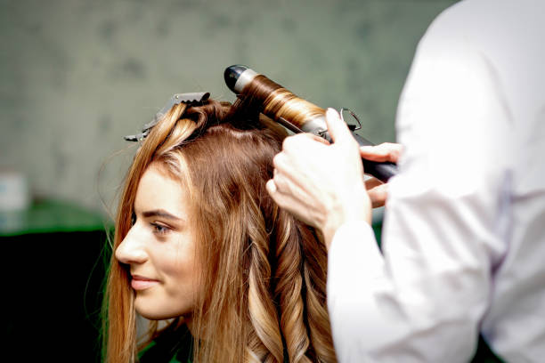 istock Hairdresser makes curls with curling iron 1298914980