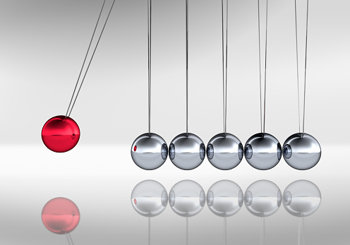 Newtons cradle with six silver and one red metal balls on white background.