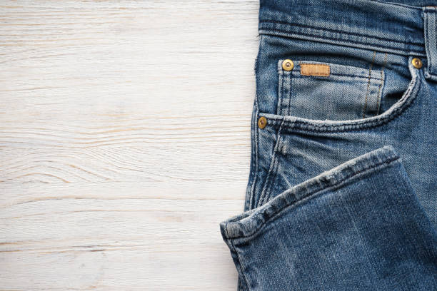 istock Folded denim pants on a wooden background, space for text. Top view. 1298920416