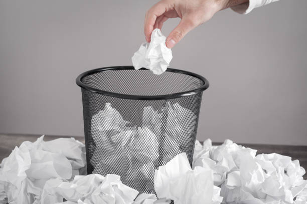 istock Man throwing crumpled paper into trash can. 1298920826