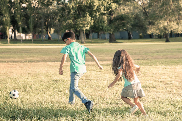 istock Group of active kids playing football on grass 1298920874