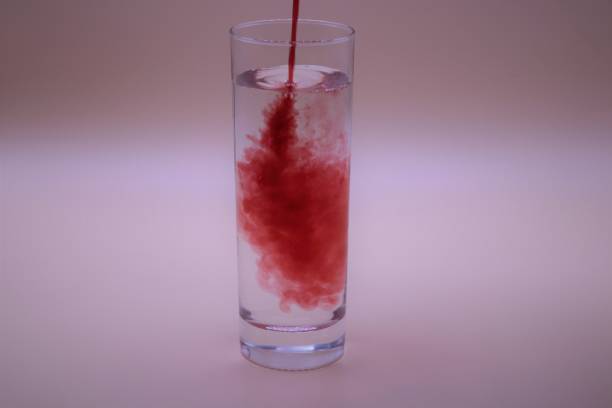 istock Red liquid being poured into a glass of water 1298925423