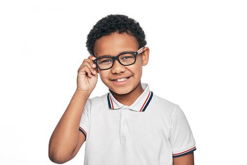 Smiling African American child with stylish eyeglasses, isolated on white background. Vision correction for children