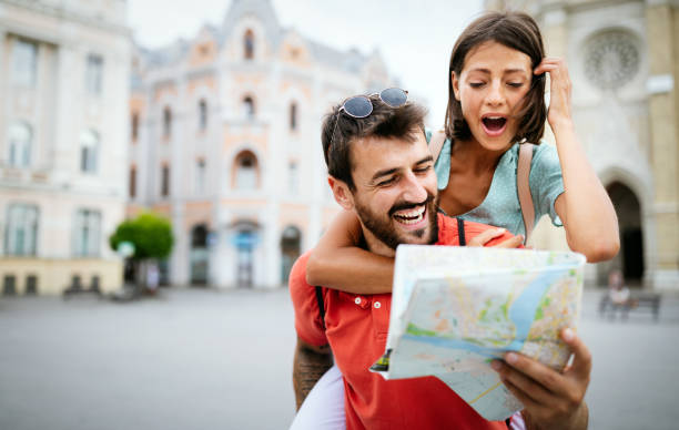 istock Happy young couple walking outdoors sightseeing and holding a map 1298925864