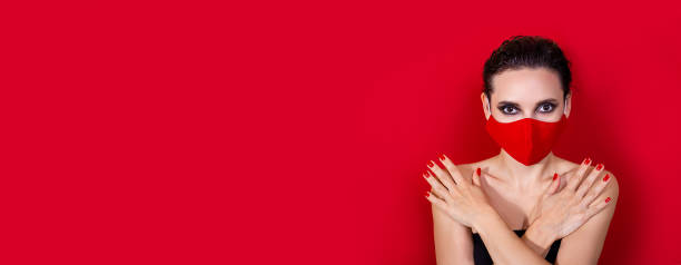 istock Horizontal banner. Woman with bright manicure dressed protective red face mask on red background 1298927234