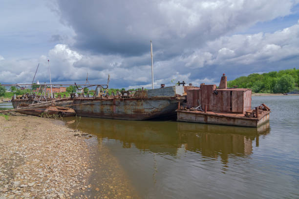 istock Old rusty river boat are used as a pier. Dramatic sky. 1298929211