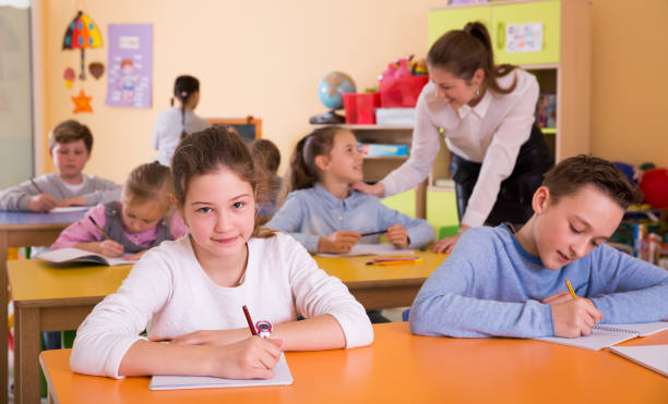 menina e grupo crianças de 9 a 10 anos de idade na aula, professora - 7 10 years - fotografias e filmes do acervo