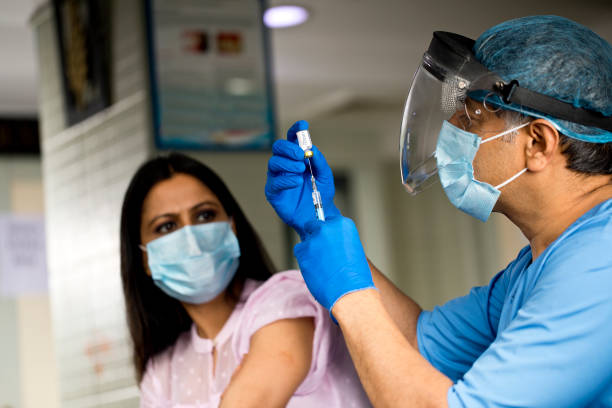 Doctor preparing Covid-19 vaccine for female patient Hands of doctor in surgical gloves pulling COVID-19 virus vaccine liquid from vial to vaccinate female patient india hospital stock pictures, royalty-free photos & images