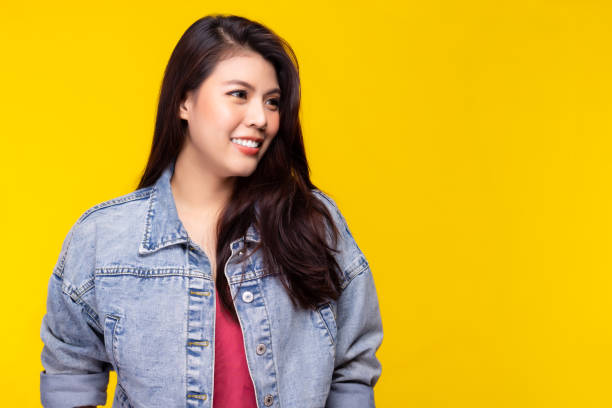 Asian girl wear denim jacket and look at copy space with smile face Asian woman has long hair Attractive young female love wearing jeans fashion She get confident Yellow background, copy space Asian girl wear denim jacket and look at copy space with smile face Asian woman has long hair Attractive young female love wearing jeans fashion She get confident Yellow background, copy space denim jacket stock pictures, royalty-free photos & images