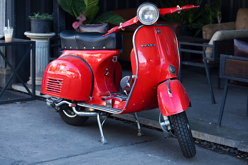 Red Vespa motorcycle parked in front of bar in Bangkok Ladprao