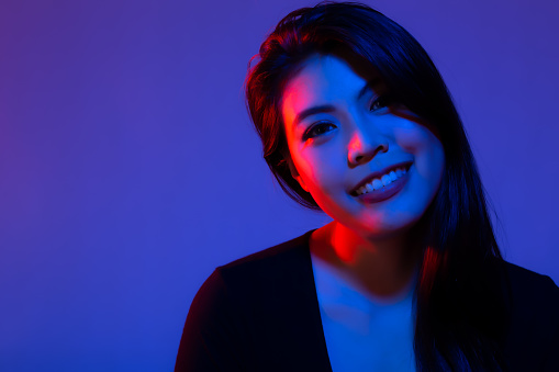 Fashion Portrait Asian Woman with creative lighting with smile face and happy Blue Background Asia Girl in Blue and red Light Beautiful female has long hair Trendy color background and copy space
