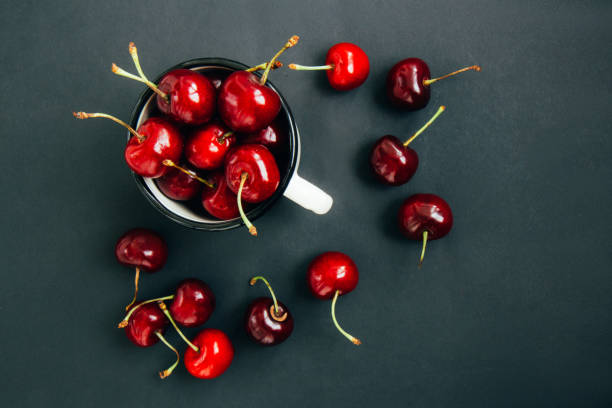 istock Red ripe cherries in a white iron mug on wooden background 1298936692
