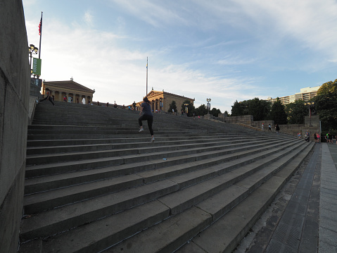 Philadelphia, USA - June 11, 2019: People running up the steps in front of the Philadelphia Museum of Art. The steps are also featured in the Rocky movie.