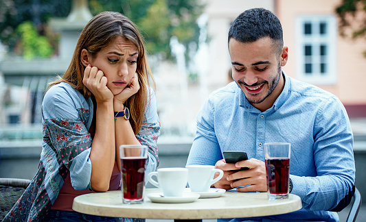Forget about the mobile phone during the meeting with a partner. Man and woman having problem in communication during the meeting in the cafe. Love and relationships