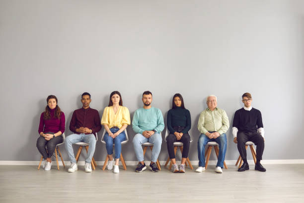 personnes multiethniques s’asseyant dans le couloir attendant leur tour pour voir le docteur ou pour avoir l’entrevue d’emploi - unemployment waiting in line waiting room interview photos et images de collection