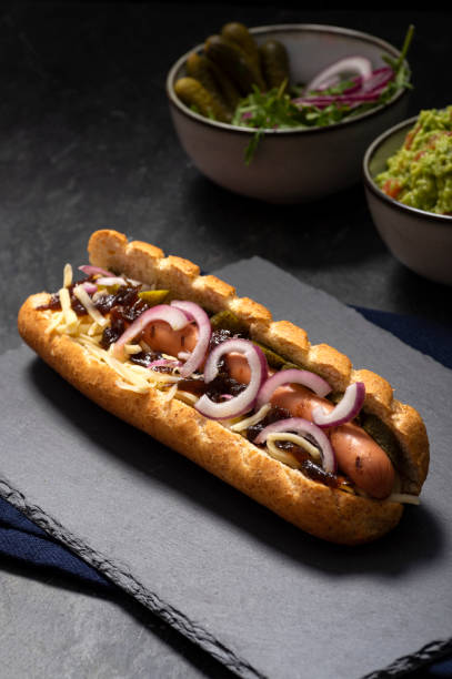 panino hot dog sporco gourmet con vari guarnire su sfondo di pietra nera. opzione sana di fast food. - salsa relish cucumber party foto e immagini stock