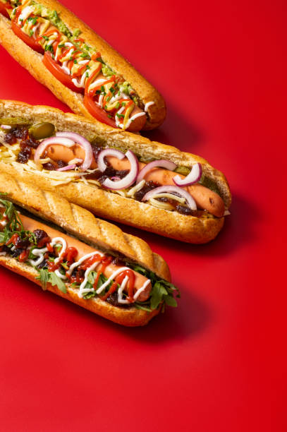 panino hot dog sporco gourmet con vari guarnire su sfondo rosso. opzione sana di fast food. - salsa relish cucumber party foto e immagini stock