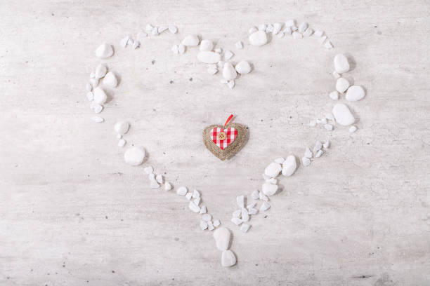 St. Valentines Day heart decorated with white rocks over bright wooden background. Top view, flat lay. Copy space