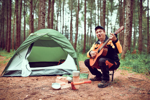 istock Senior Male Playing Guitar And Enjoying Camping 1298946400