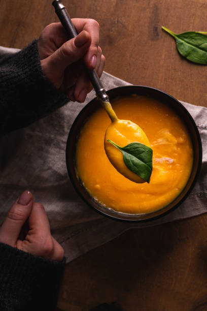 istock Hand holding a spoon with pumpkin soup 1298950133