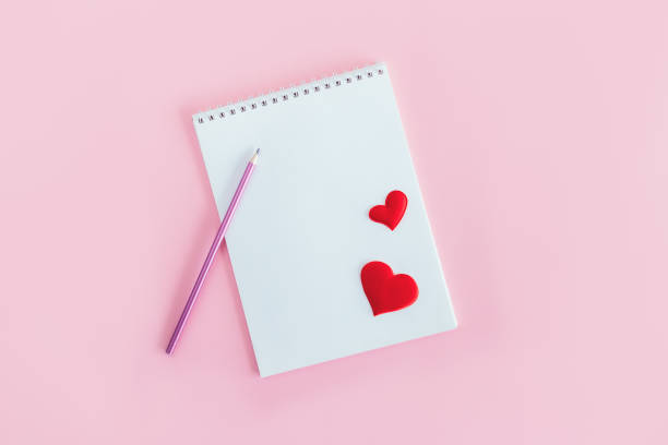 istock Notebook with blank page, pencil and red hearts on a pink background. 1298957252