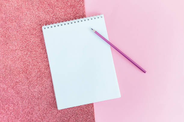istock Notebook with blank page and pencil on a pink background. 1298957270