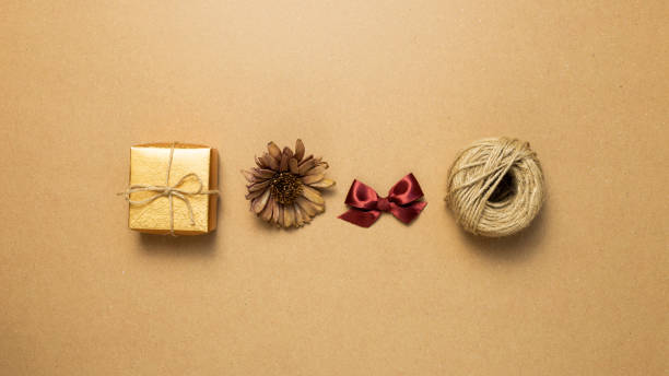 gift box, dry flower, ribbon, string on brown kraft paper background. flat lay, top view, copy space - string package brown paper imagens e fotografias de stock