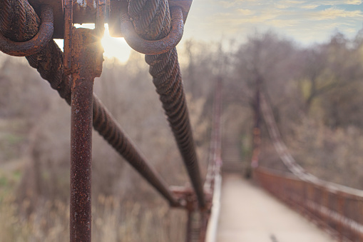 An old rusty steel bridge cable attachment at sunset or sunrise in early spring or late fall