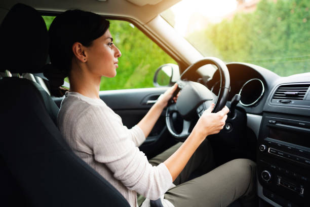 istock Young woman driving a car on a sunny day 1298961353