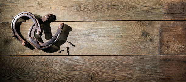 istock Two old rusty horse shoes on a rustic wooden 1298961389