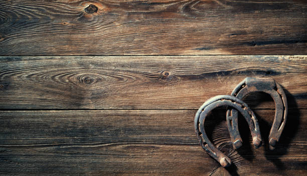 istock Two old rusty horse shoes on a rustic wooden 1298961495