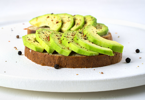 Avocado sandwiches in a white plate on a light background. Side view. The concept of proper nutrition.