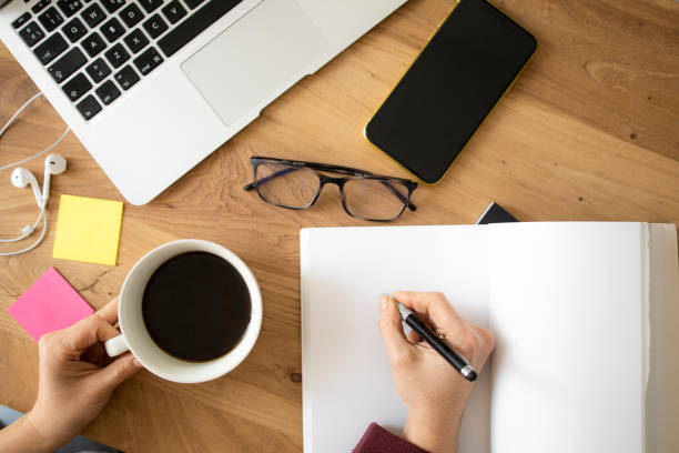 istock Work table in the office or at home with computer, mobile, hands, notebook, glasses and pen 1298964644