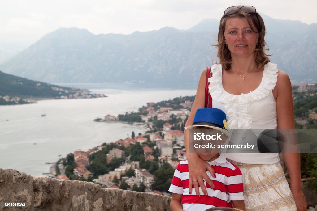 concept of family adventure. Mother traveling with children is d concept of family adventure. Mother traveling with children is depicted on the observation deck on the mountain overlooking the famous spectacular view of the Bay of Kotor, Montenegro Photography Stock Photo
