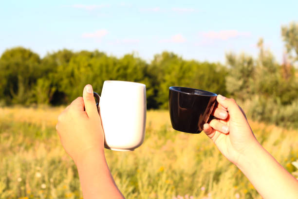 istock Two hands with cups of tea against the sky. 1298965291