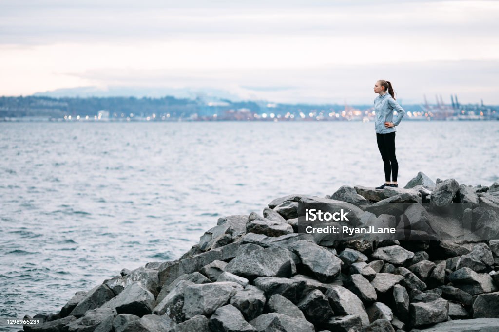 Morning Runner Takes a Break at Waterfront Trail A young adult woman pauses from her jog at the Ruston Way waterfront in Tacoma, Washington, USA to take in the beauty of setting.  A brisk and invigorating run to start the day right and healthy. Puget Sound Stock Photo