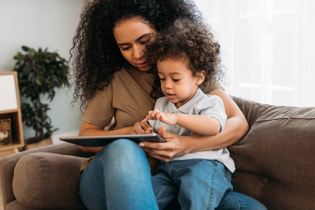 istock Mother and son sitting on the sofa and using digital tablet 1298969207
