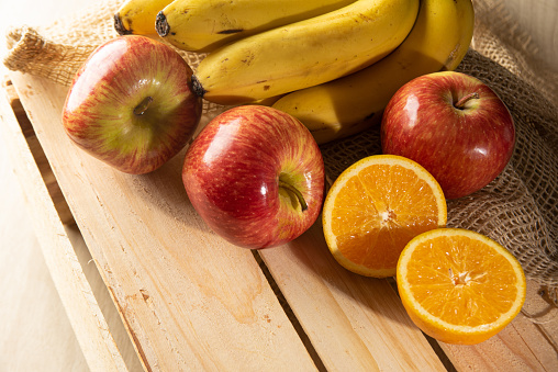 Orange, orange cut in half, apples and bananas on rustic wooden surface and rustic fabric, selective focus.